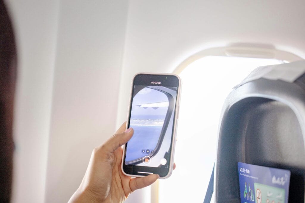 A person filming the scenic view from an airplane window using a smartphone.